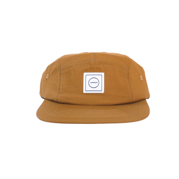 A beige nylon five-panel hat with an adjustable velcro back and fabric eyelets on the side panels, displayed in a front view.